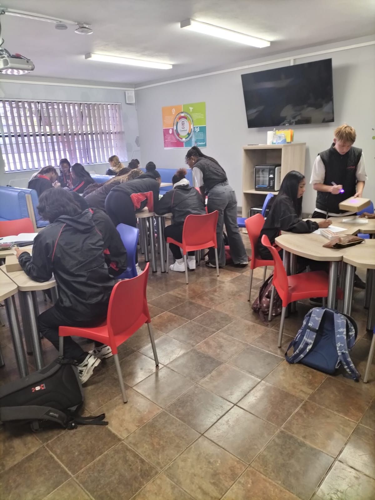 A group of people are sitting at tables in a classroom.