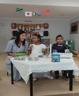A woman is sitting at a table with two children.