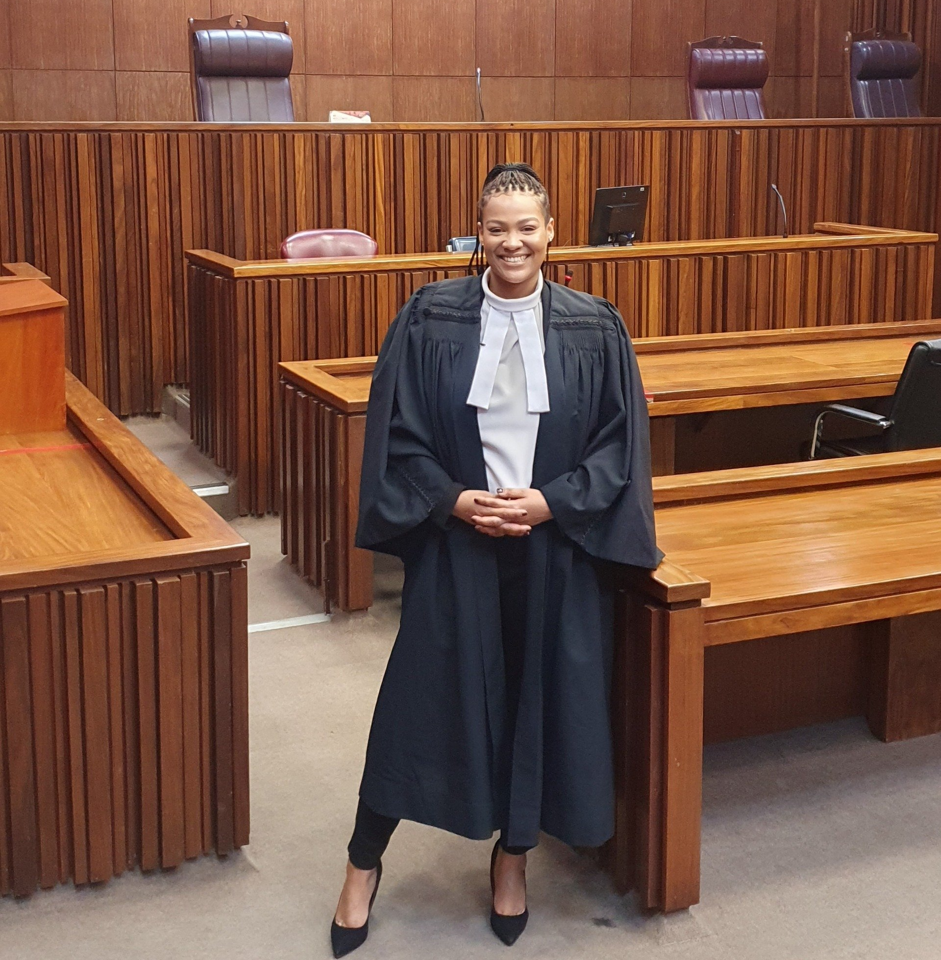 A woman in a graduation gown is standing in a courtroom