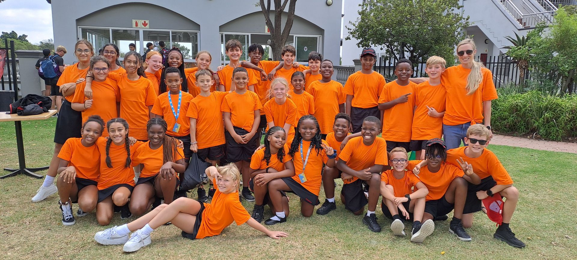 A large group of children wearing orange shirts are posing for a picture.