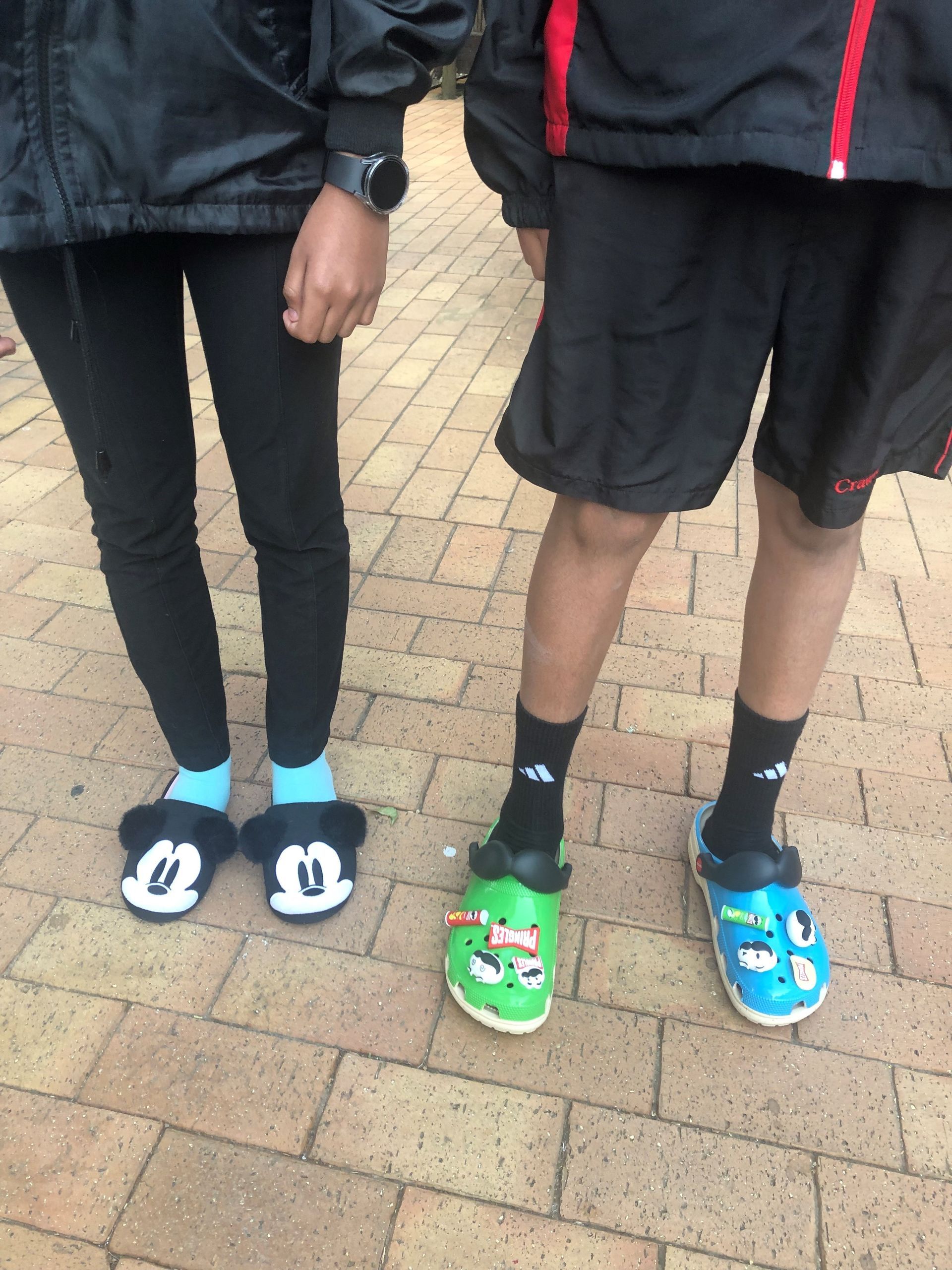 A man and a woman wearing mickey mouse slippers and crocs