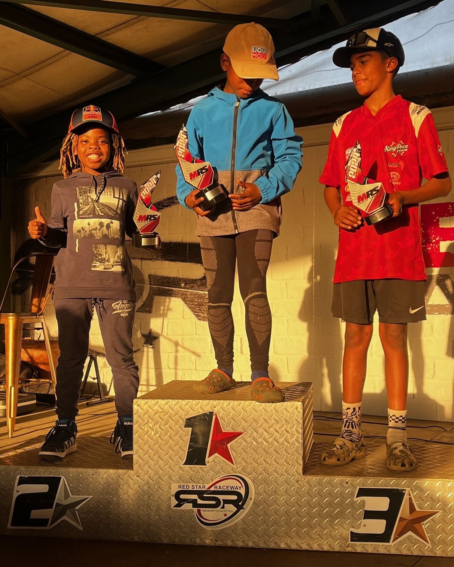 Three young boys are standing on a podium with the number 1 on it