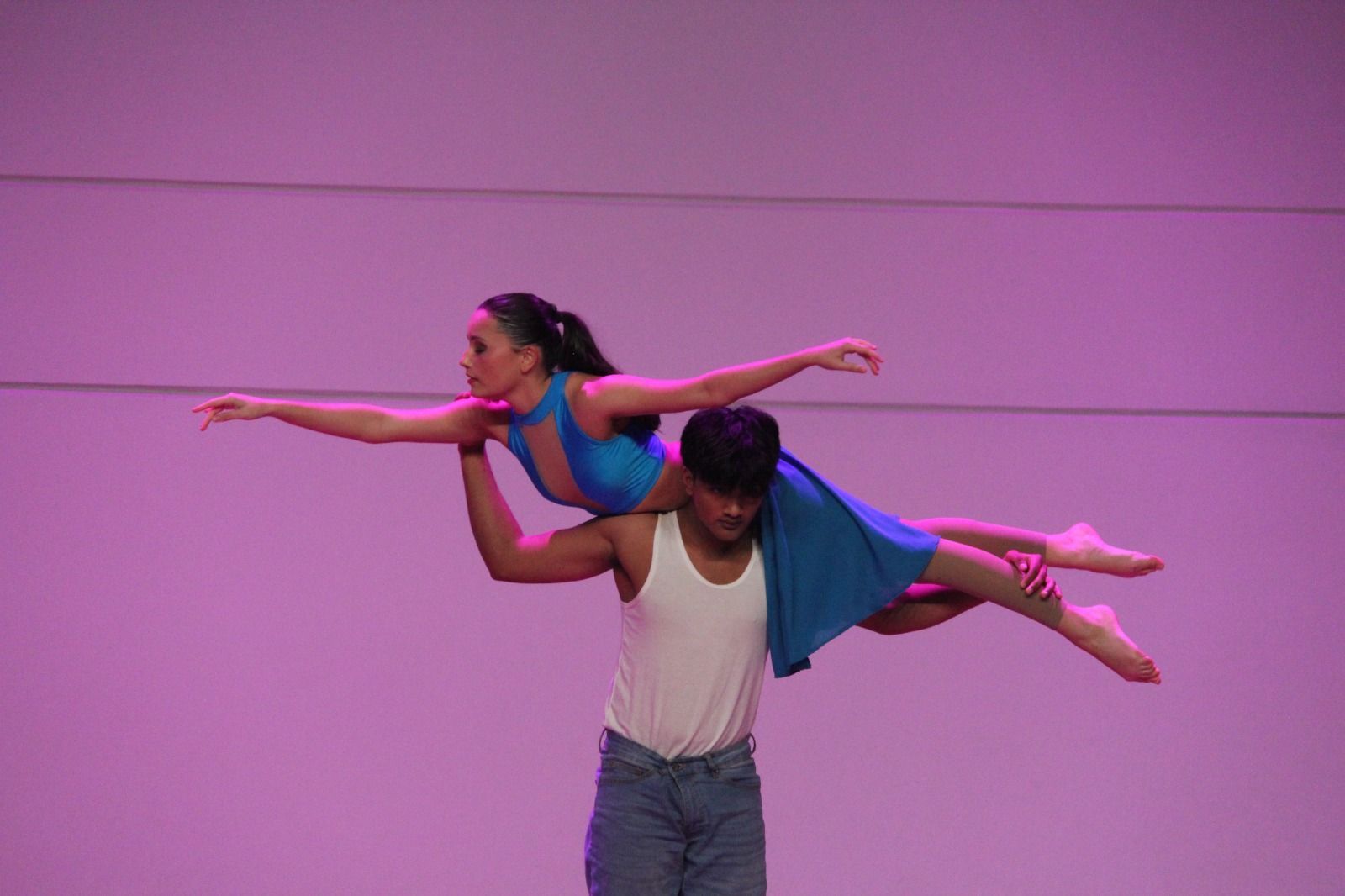 A man is carrying a woman in the air on his shoulders.