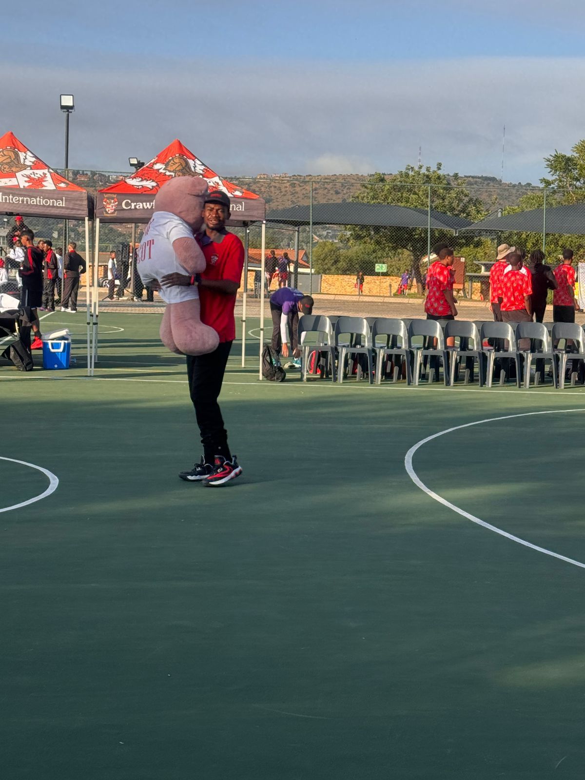 A man is holding a stuffed animal on a basketball court.