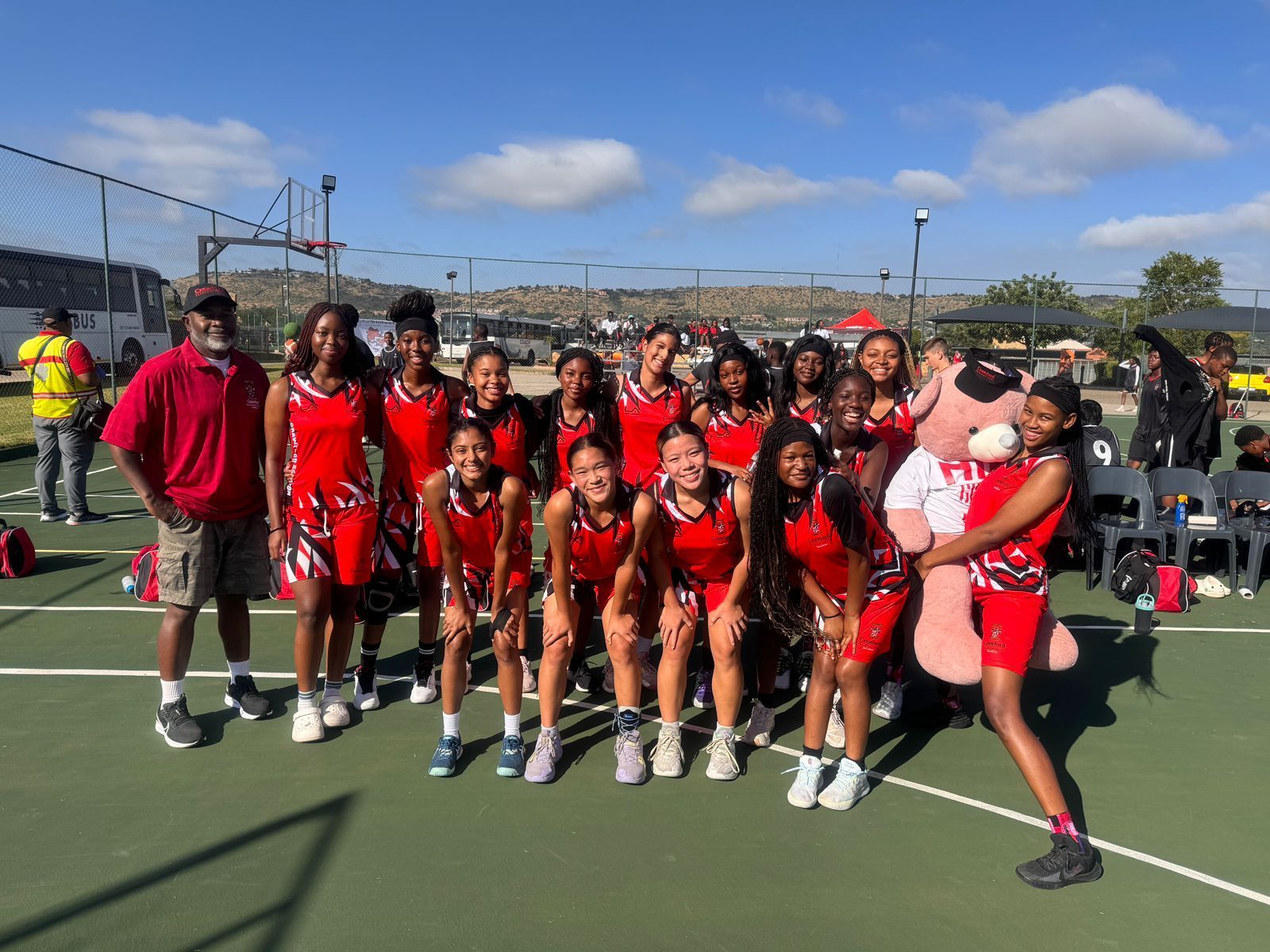 A group of young girls are posing for a picture on a basketball court.
