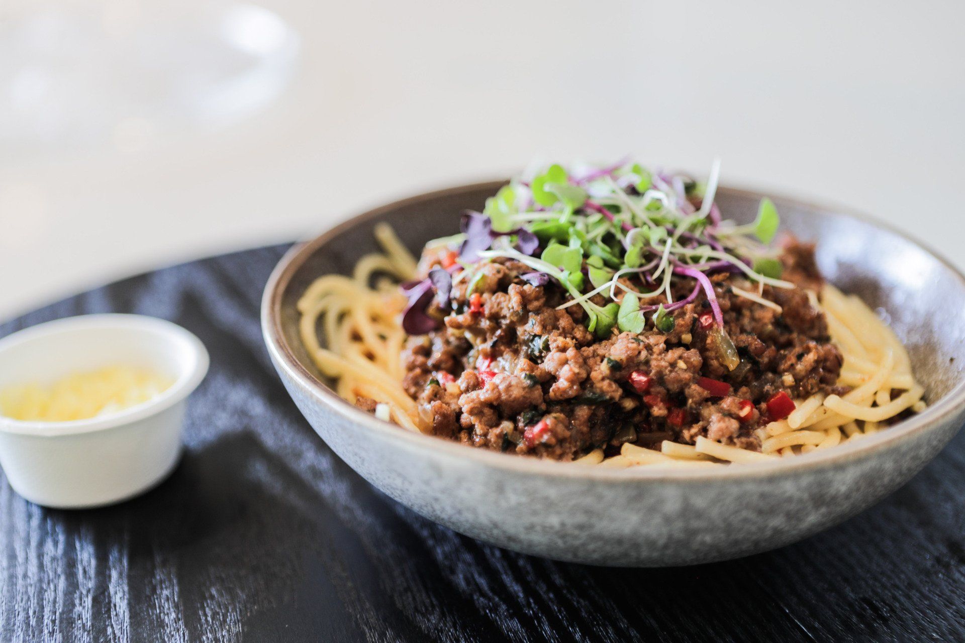 a bowl of spaghetti with meat and vegetables on a table .