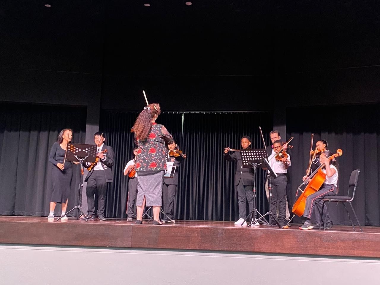 A group of people are playing violins on a stage.