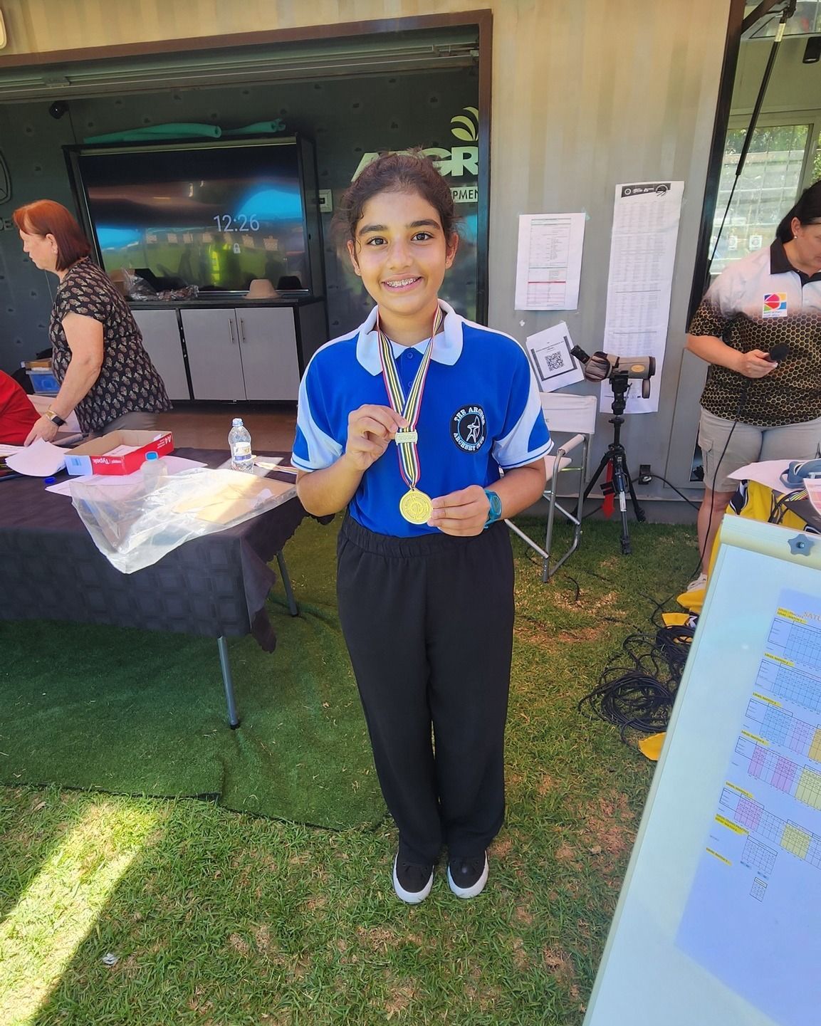 A young girl is holding a gold medal in her hand.