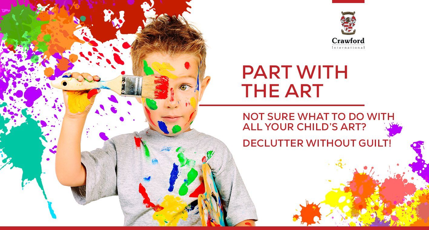 A young boy with paint on his face is holding a brush.