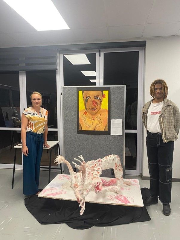 Two people are standing next to a painting of a woman.