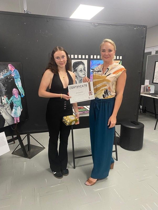 Two women are standing next to each other in a room holding a certificate.