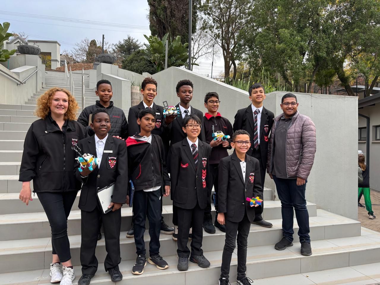 Group of students in formal wear with adults standing on outdoor steps.