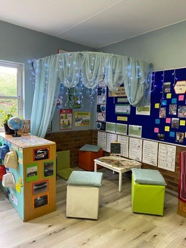 A classroom with a canopy , a table , stools and a globe.