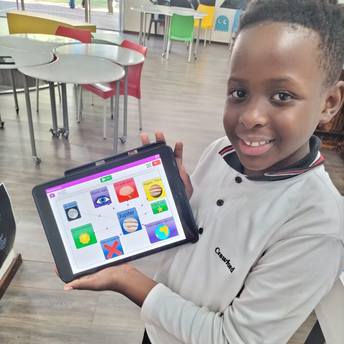 A young boy is holding a tablet in his hands and smiling