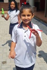 A little girl is holding a red paper airplane in her hand.