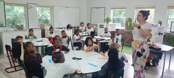 A woman is standing in front of a classroom full of children.