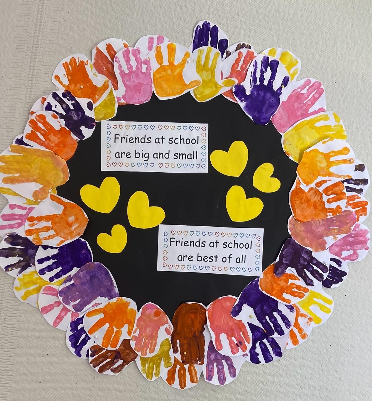 A wreath made out of children 's handprints and hearts says friends at school are big and small