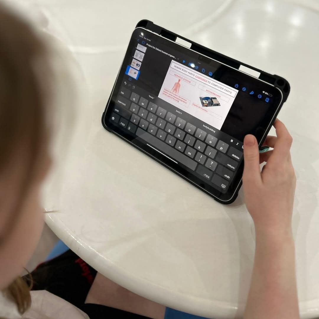 Person using a tablet with a keyboard. The tablet shows a diagram on the screen. The person is sitting at a white table.