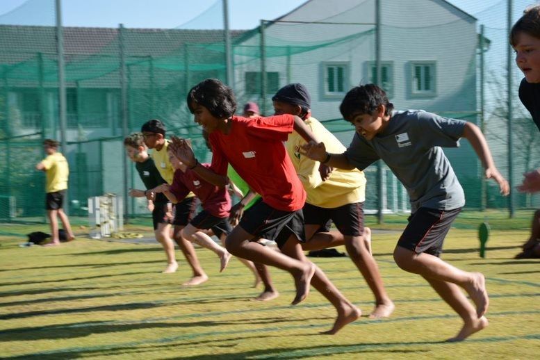 A group of young boys are running on a grassy field.