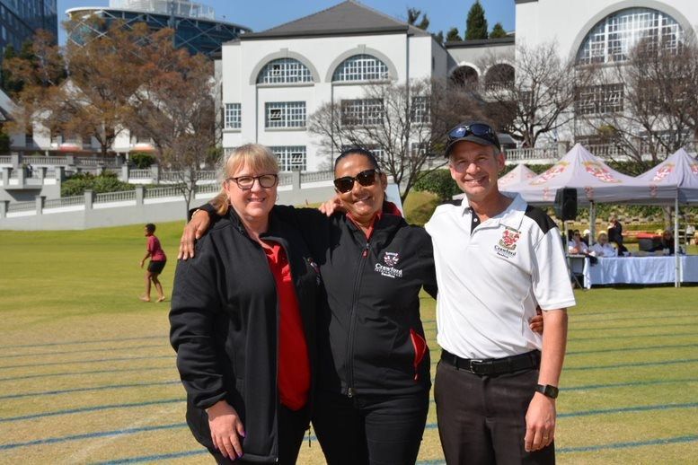 Three people are posing for a picture on a field.