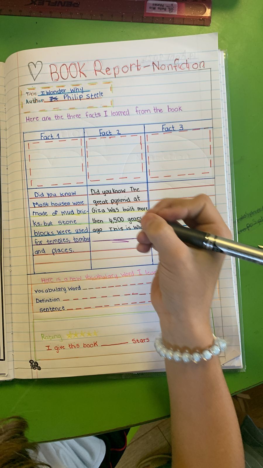 A person is writing a book report in a notebook