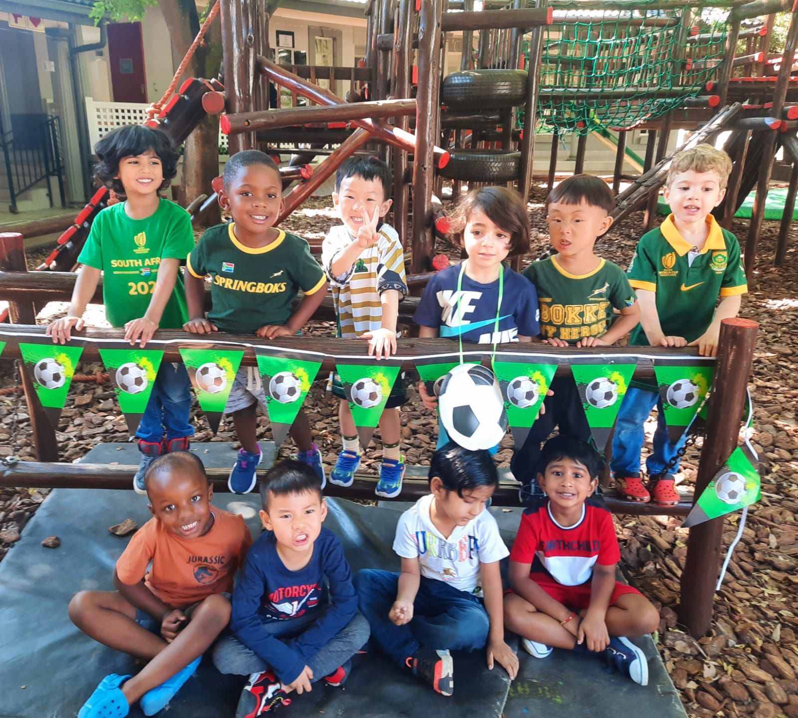 A group of children are posing for a picture in front of a playground