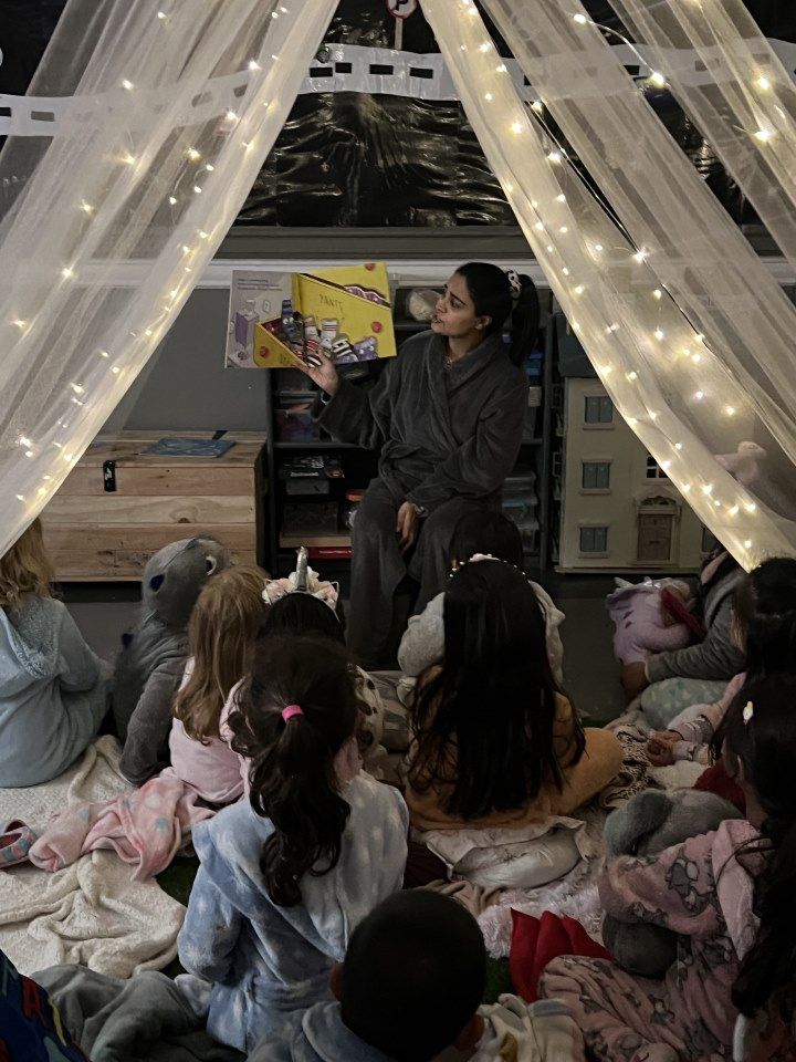 A woman is reading a book to a group of children in a tent.