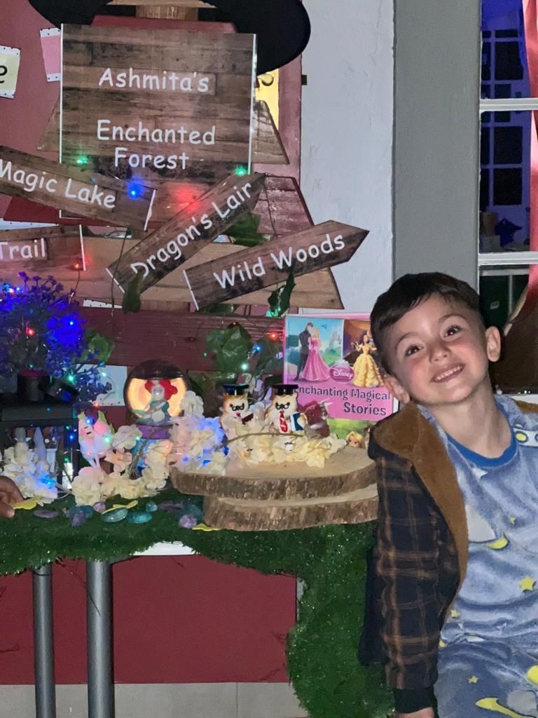 A young boy is sitting in front of a sign that says enchanted forest.
