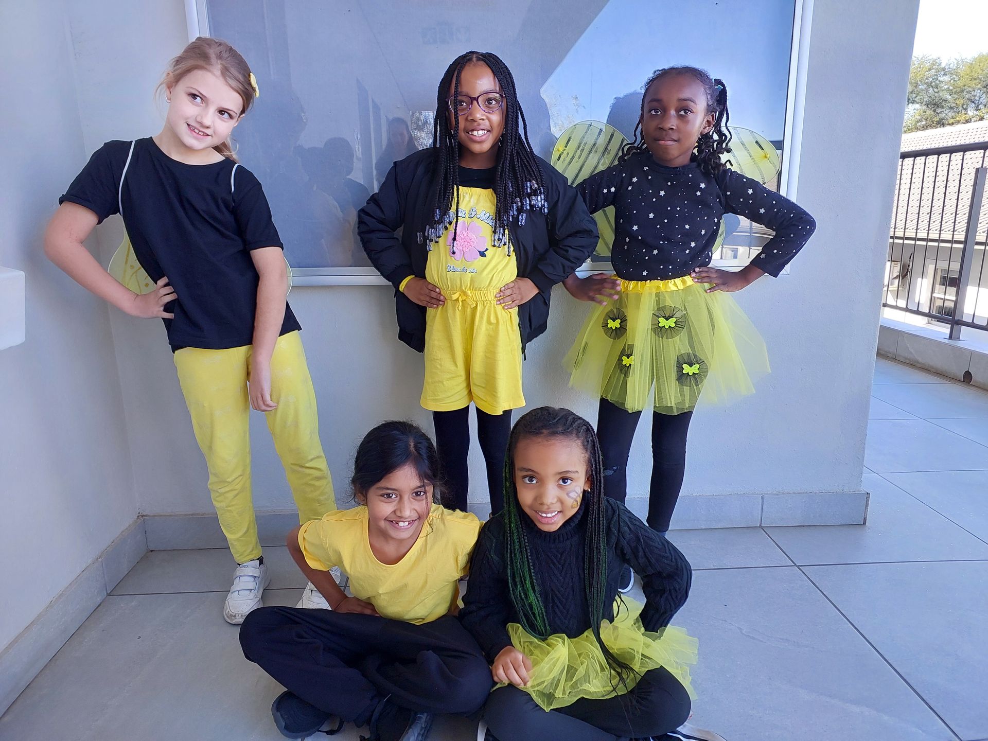 Five children in black and yellow outfits, posing outside.