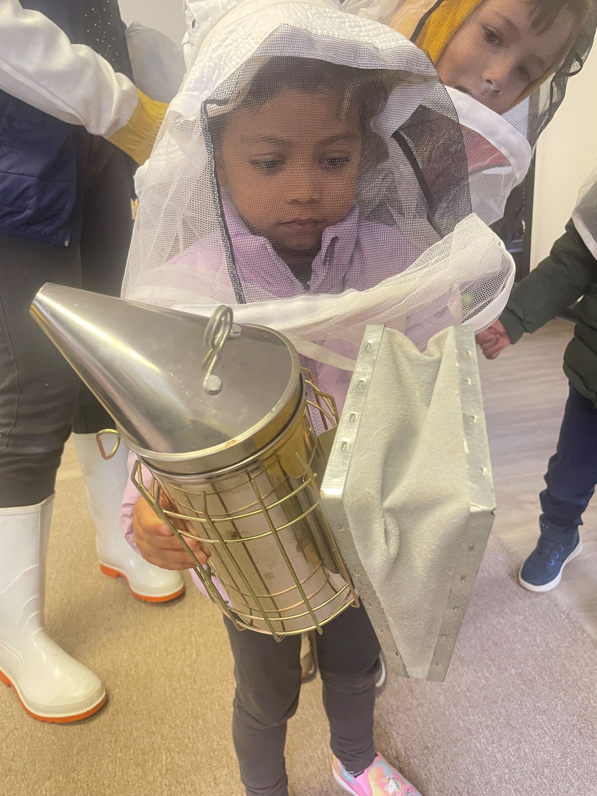 Little girl holding bee smoker
