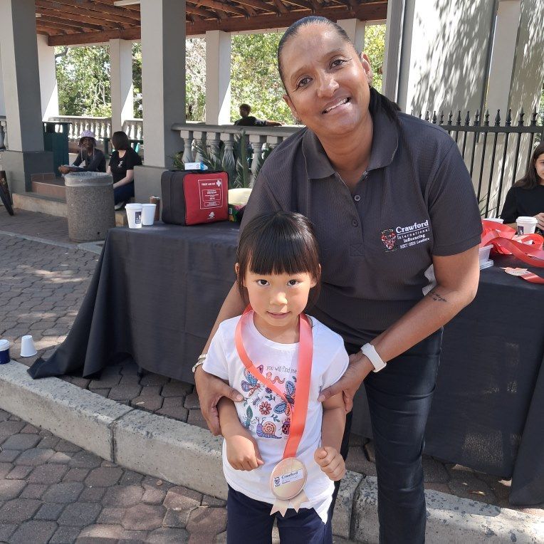 A woman in a black shirt is holding a little girl with a medal around her neck