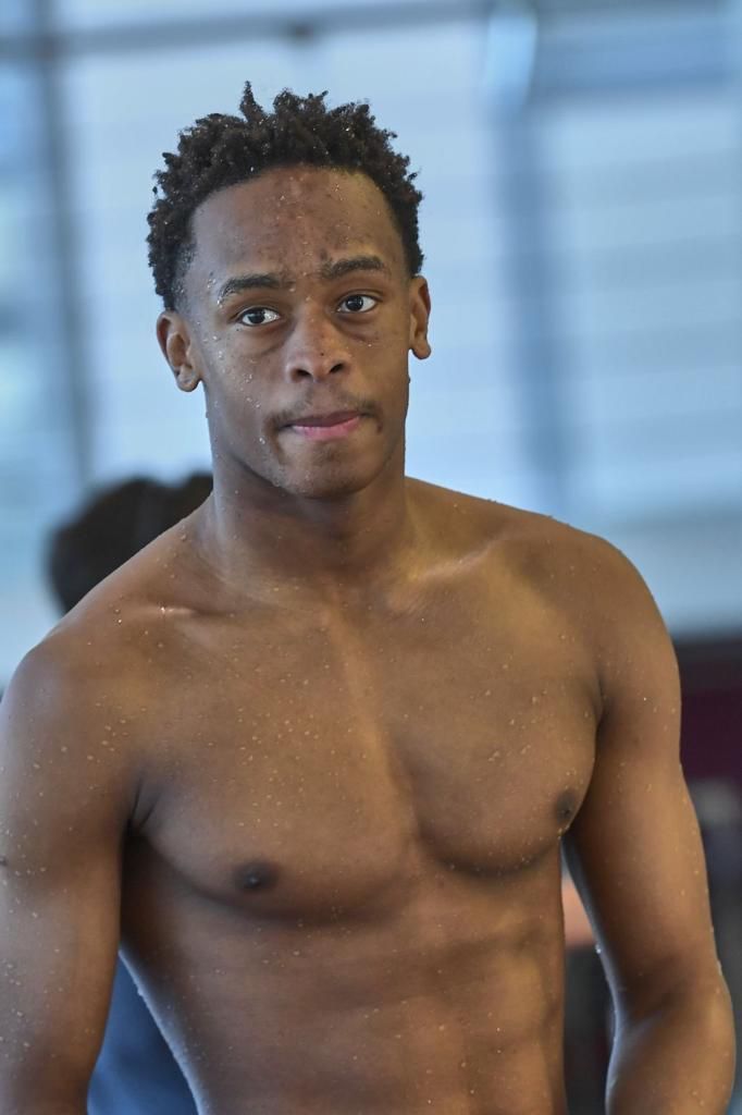 A shirtless man is standing in a pool and looking at the camera.