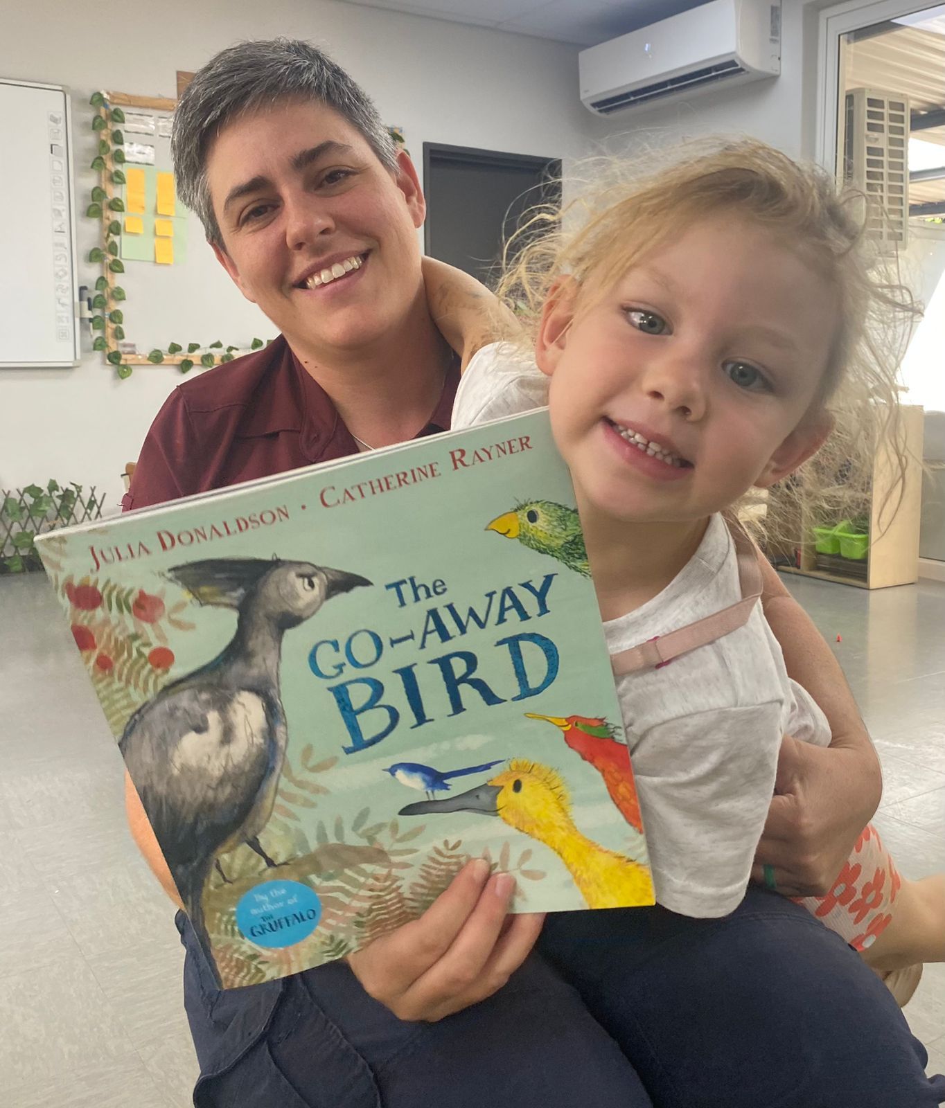 A little girl is holding a book titled the co-away bird