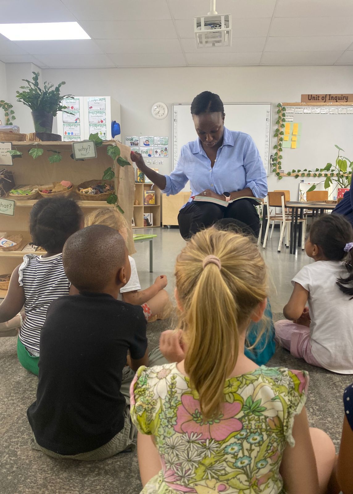 A woman is reading a book to a group of children in a classroom.