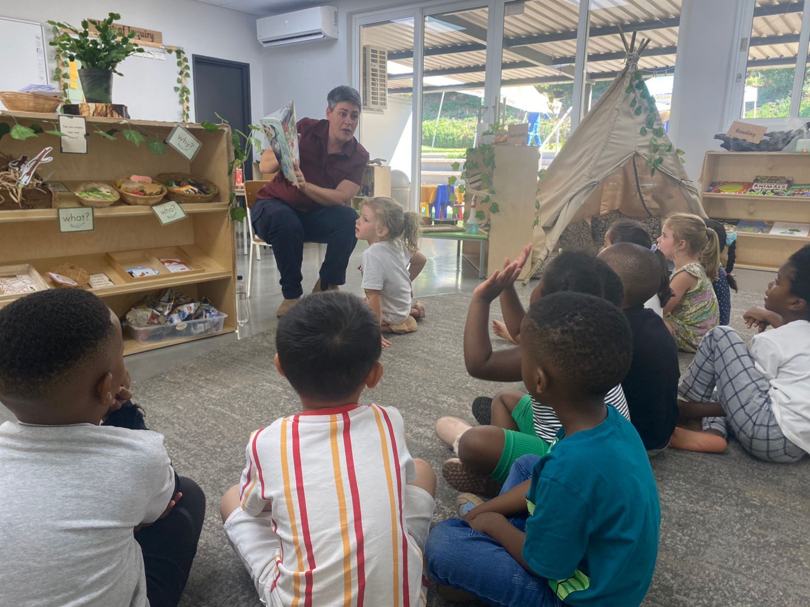 A man is reading a book to a group of children in a classroom.