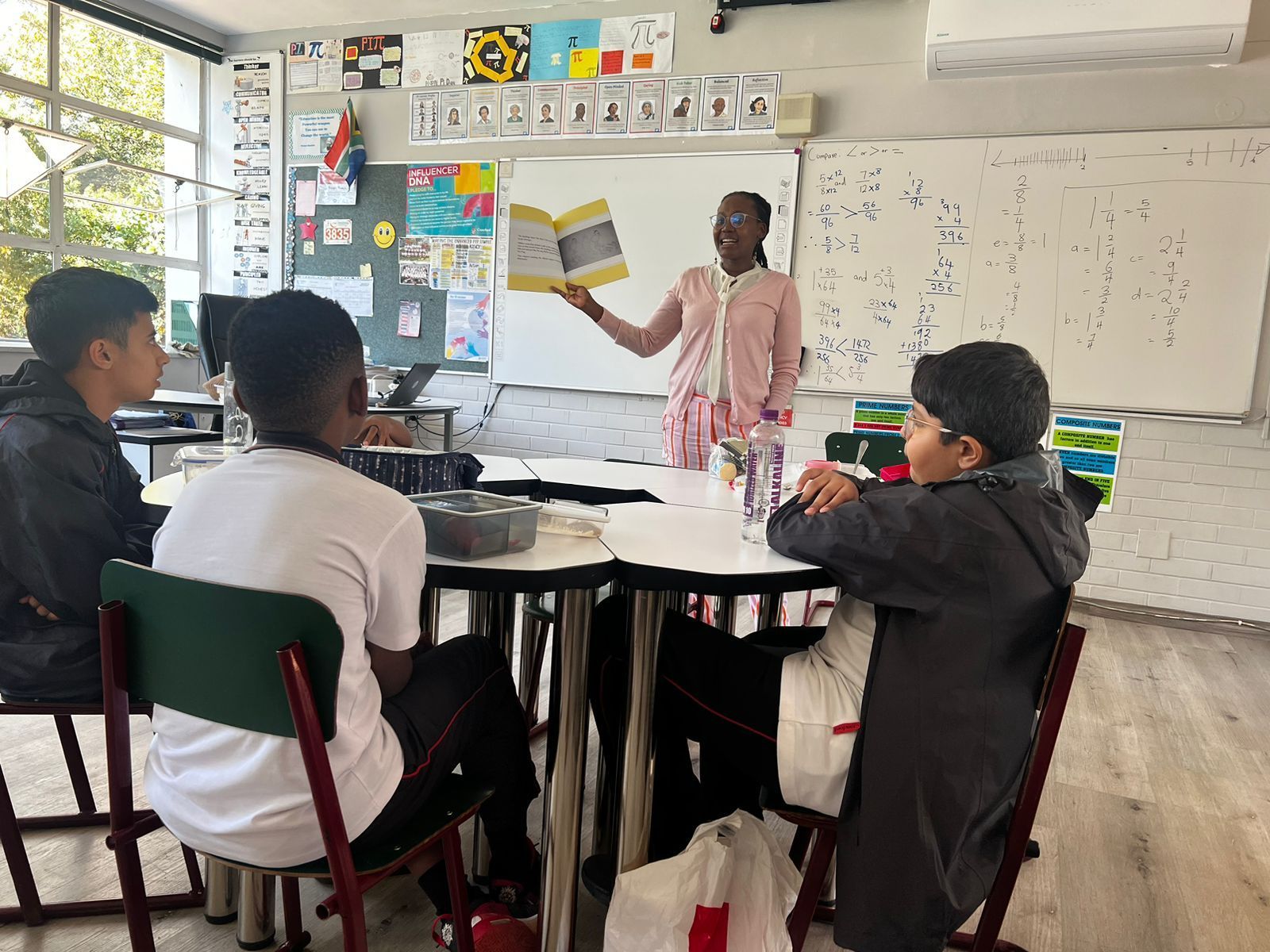 A teacher is reading a book to a group of children in a classroom.