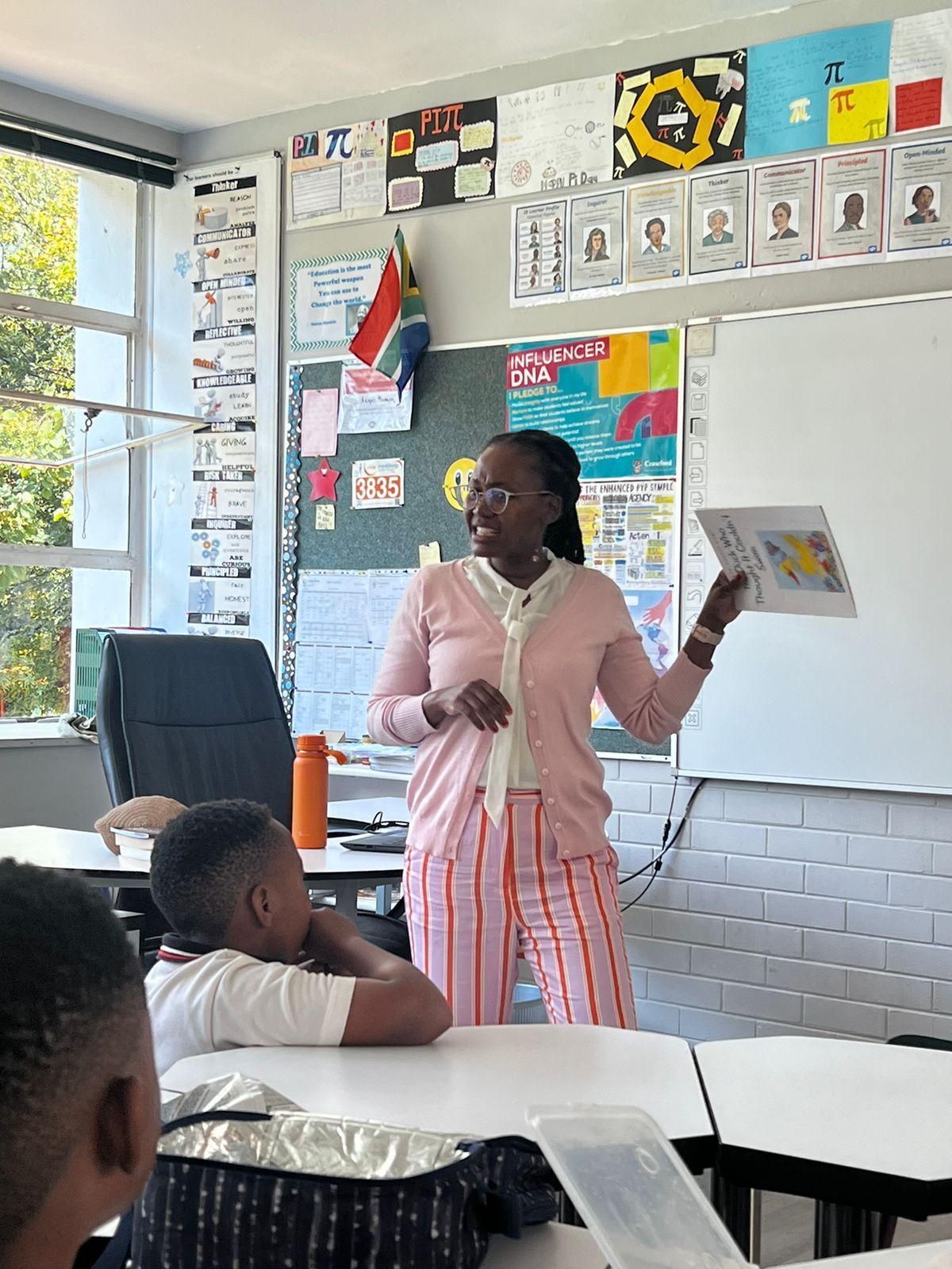 A woman is giving a presentation to a group of children in a classroom.