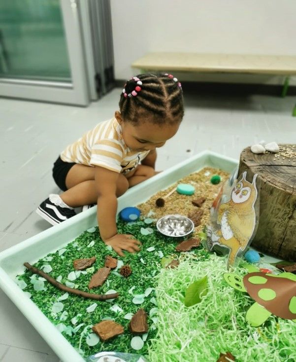 A little girl is playing in a sensory bin