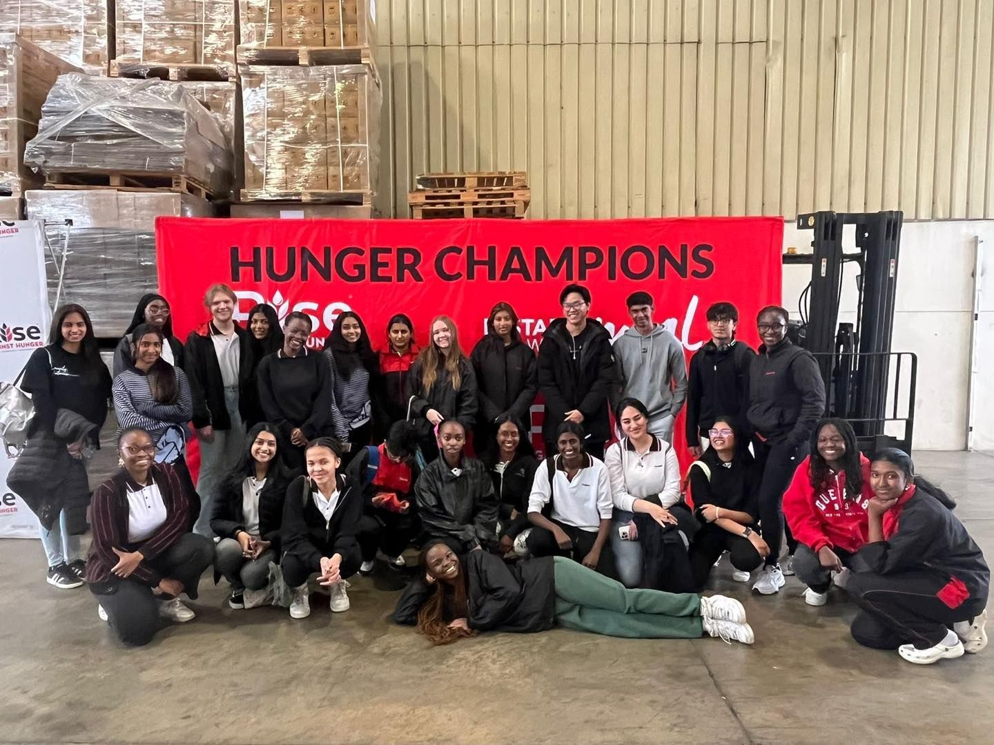 A group of people are posing for a picture in front of a sign that says hunger champions.
