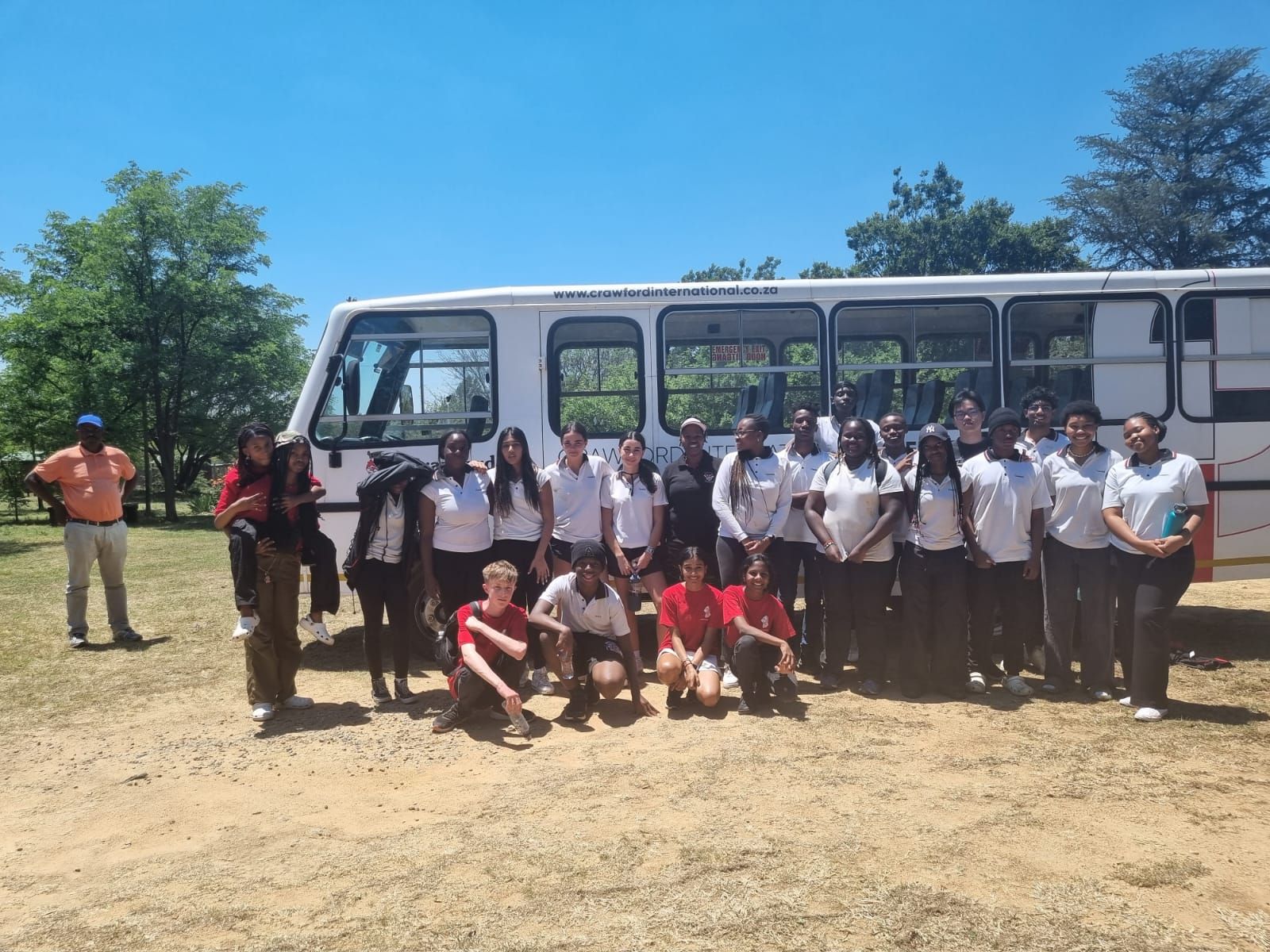 A group of people posing for a picture in front of a bus