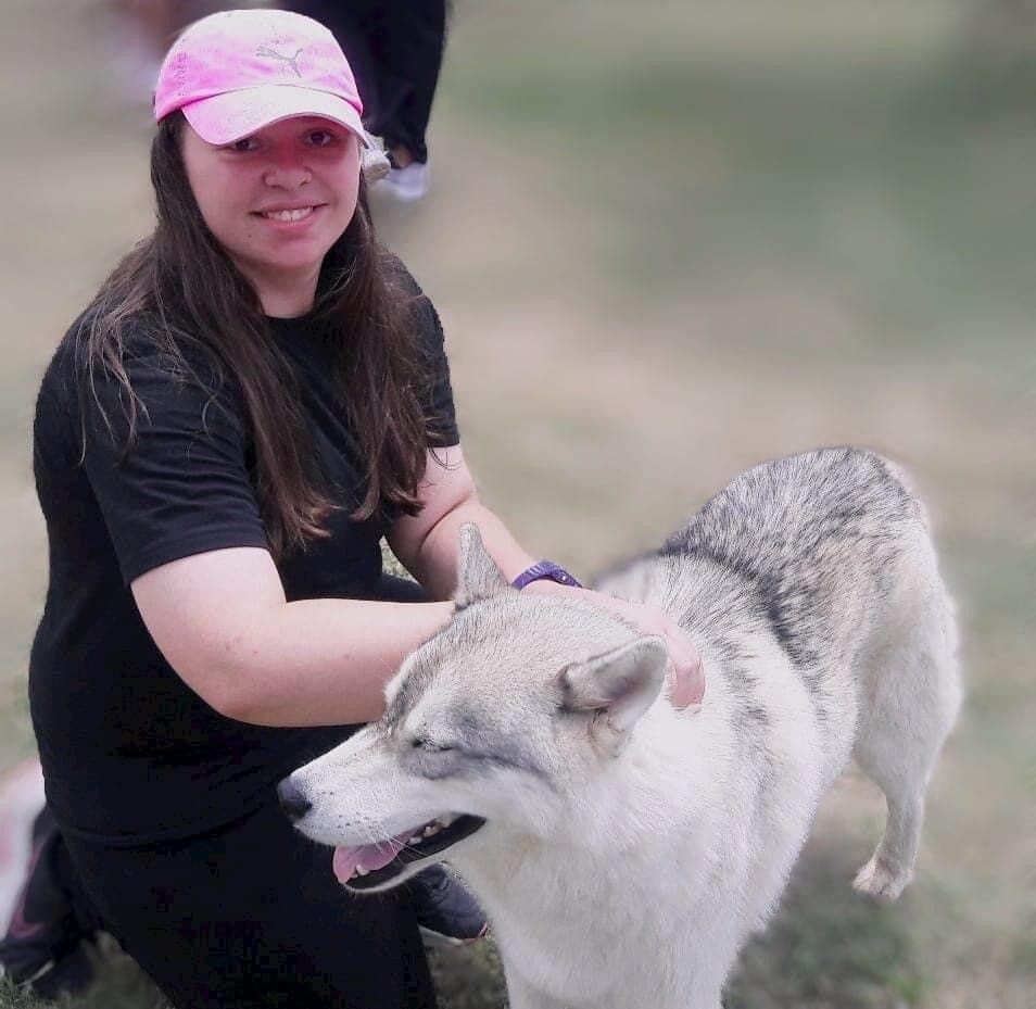 A woman in a pink hat is petting a dog