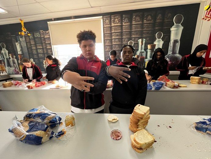 Two boys are standing in front of a table with sandwiches on it.