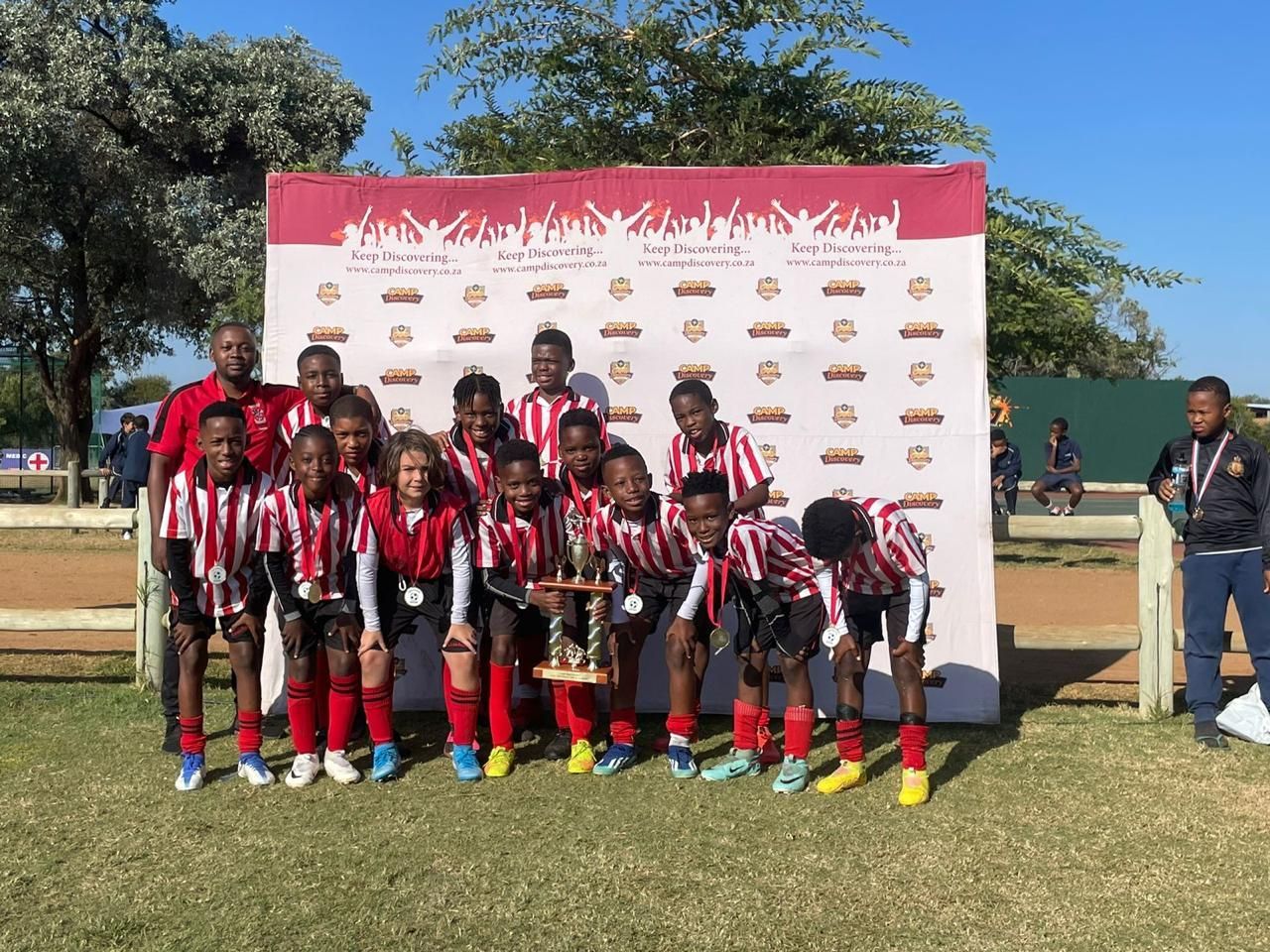 A group of children are posing for a picture with a trophy.