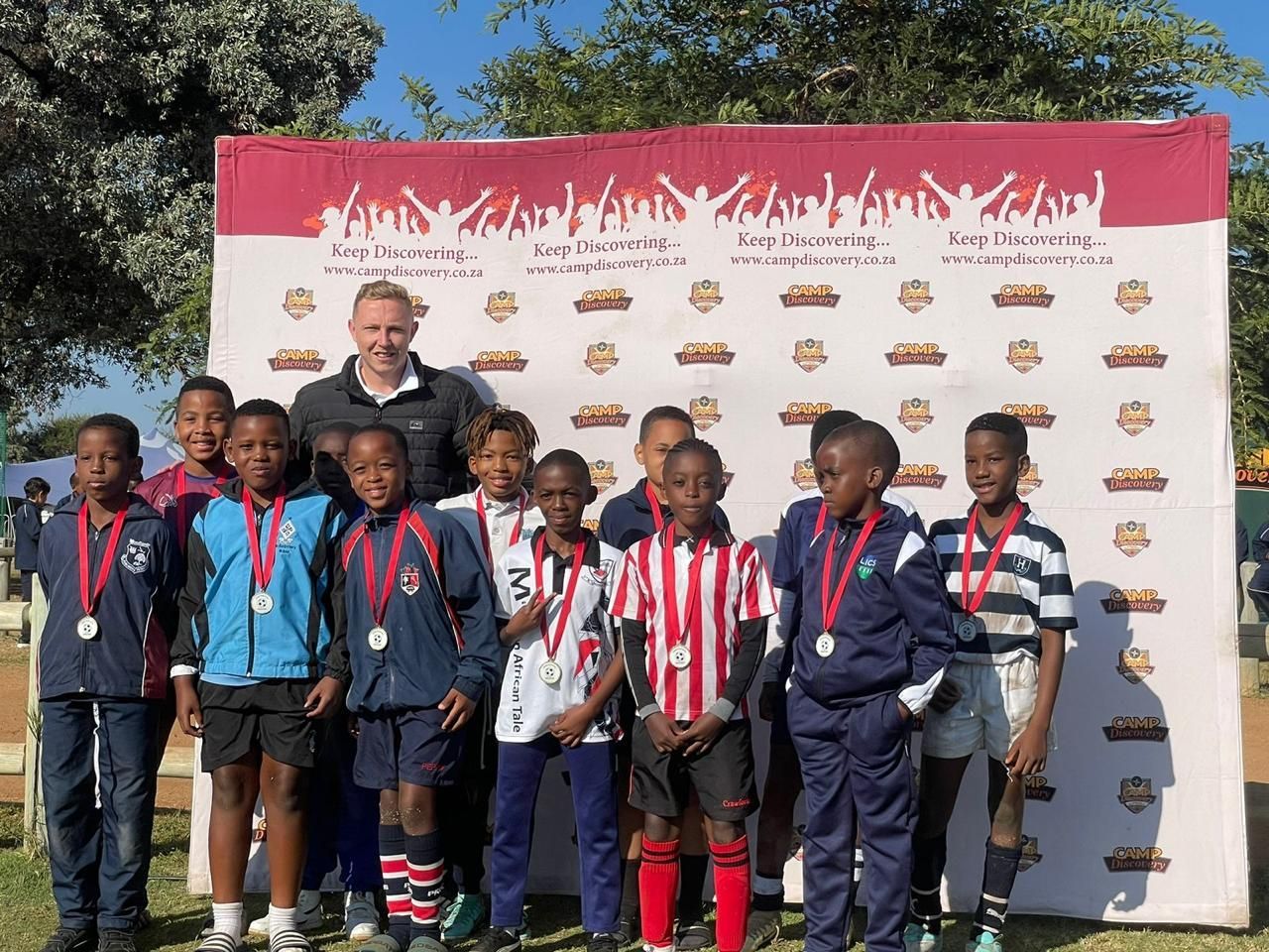 A group of children are posing for a picture with medals around their necks.