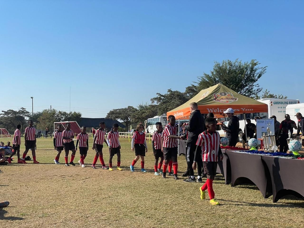 A group of children are standing in a line on a soccer field.