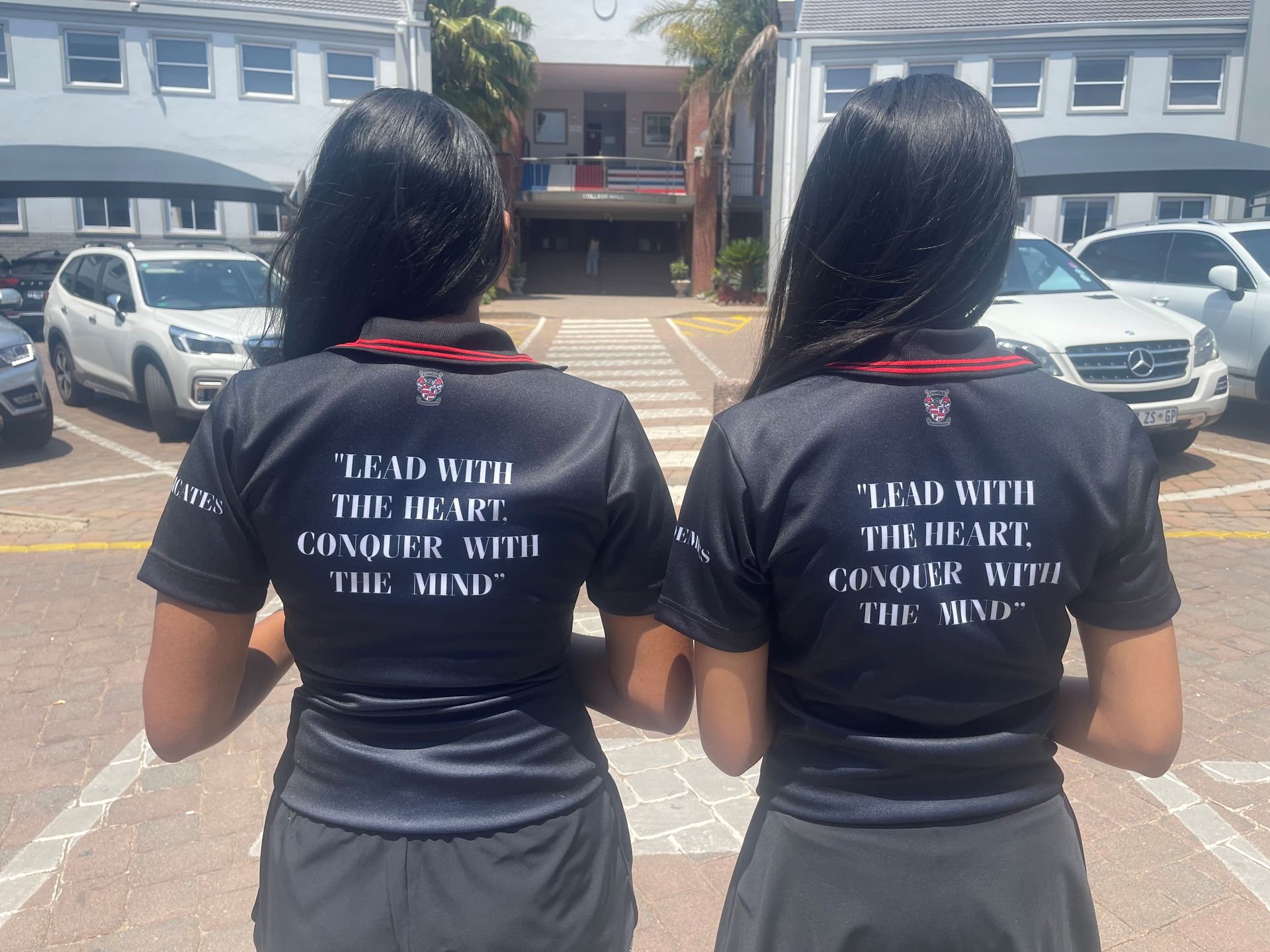 Two women wearing black shirts that say lead with the heart conquer with the mind