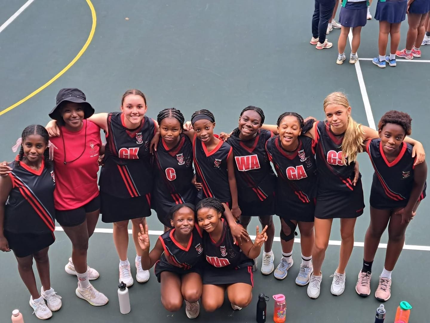 A group of young girls are posing for a picture on a basketball court.