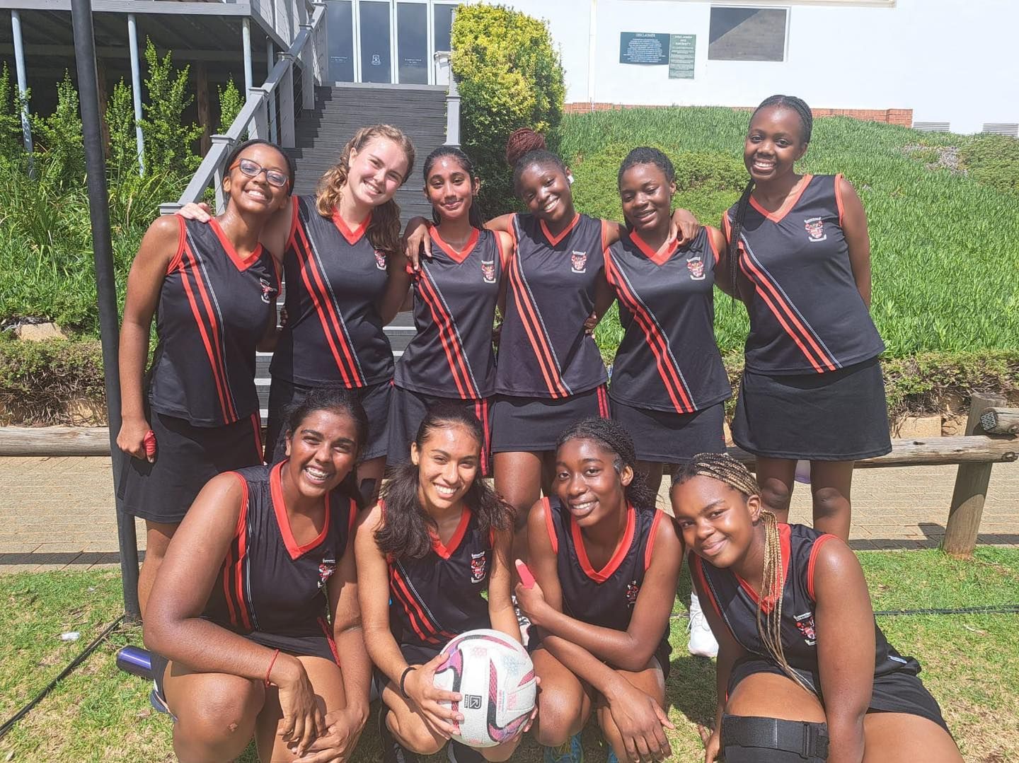 A group of young women are posing for a picture while holding a volleyball.