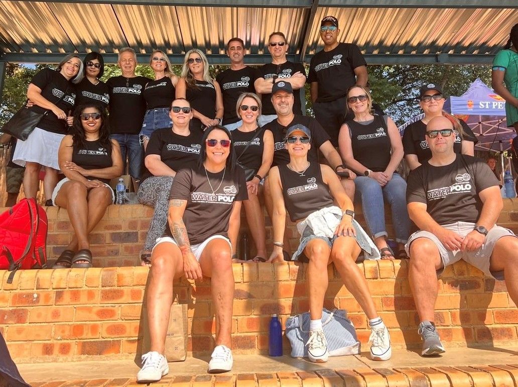 A group of people are posing for a picture while sitting on a brick wall.