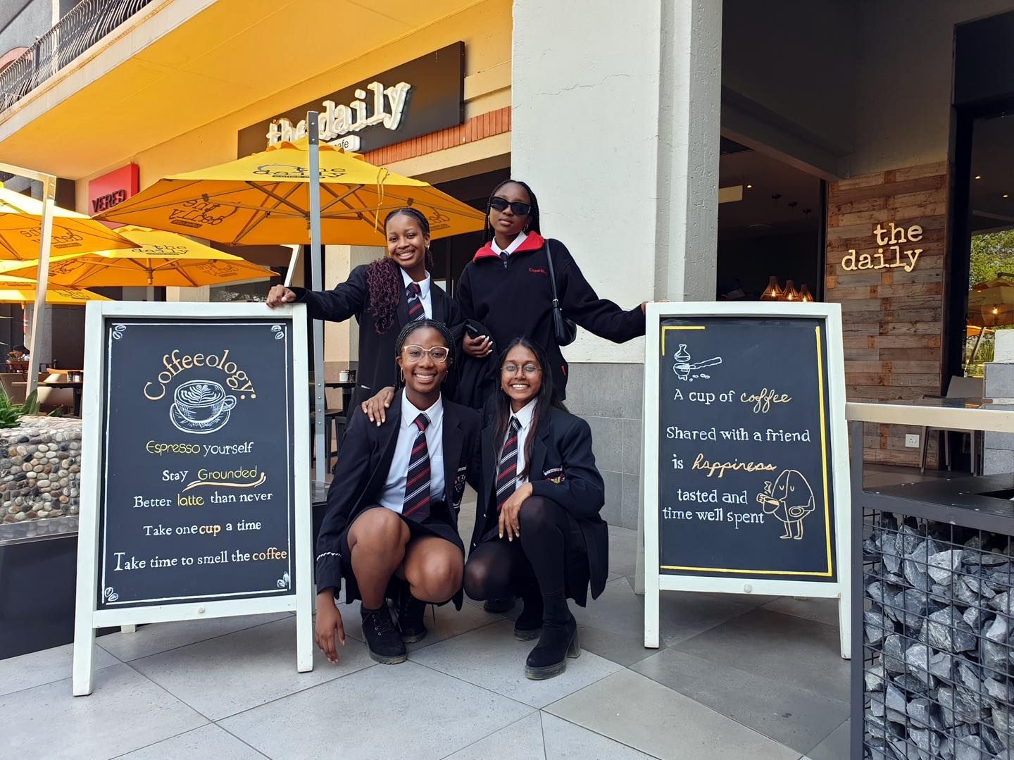 A group of young girls are posing for a picture in front of a restaurant.
